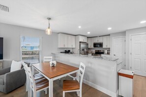 A modern kitchen with white cabinets, a wooden dining table, and a built-in island with a stainless steel refrigerator and microwave. - Modern Waterfront Tampa Home w/ Balconies (Tampa)
