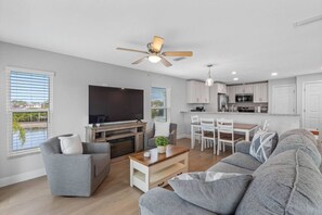 A modern living room with a flat-screen TV, grey sofas, a coffee table, and a ceiling fan. - Modern Waterfront Tampa Home w/ Balconies (Tampa)