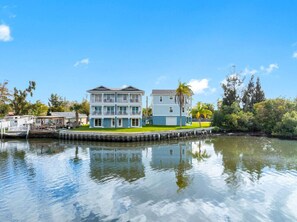 A waterfront property with a multi-story building, a dock, and a calm water body. - Modern Waterfront Tampa Home w/ Balconies (Tampa)