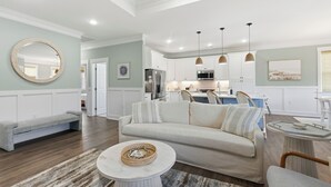 Una sala de estar moderna con un sofá, una mesa de centro y una cocina al fondo.