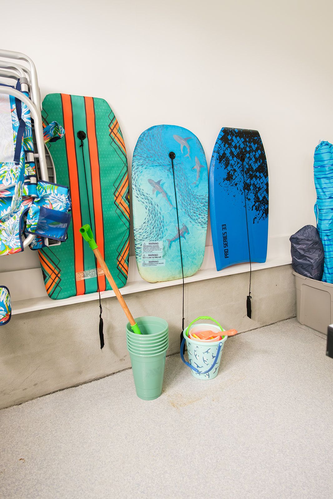 A wall with surfboards and a bucket with a paddle.