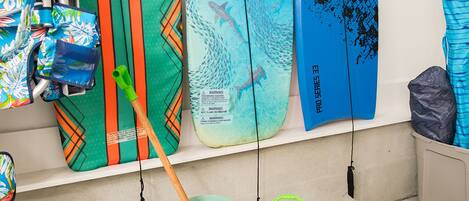 A wall with surfboards and a bucket with a paddle.