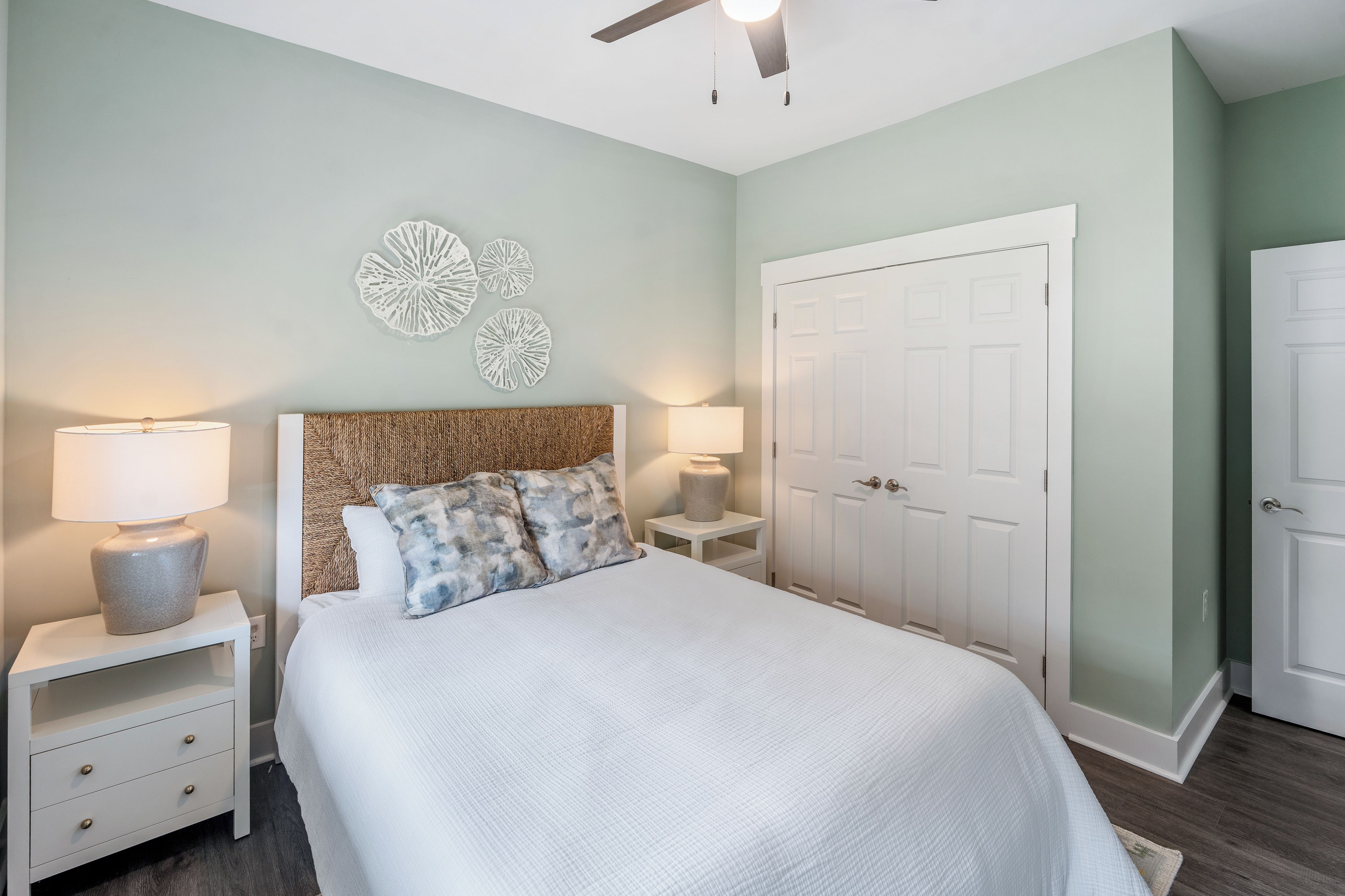 A bedroom with a bed, nightstands, wall decor, a ceiling fan, and a wardrobe.