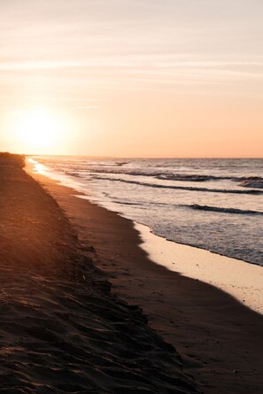 A beach with a sunset, waves, and a sandy shore. - Coastal Retreat~Ocean Isle Beach. Relax by Fire Pit, with beautiful Pond View. (Ocean Isle Beach)