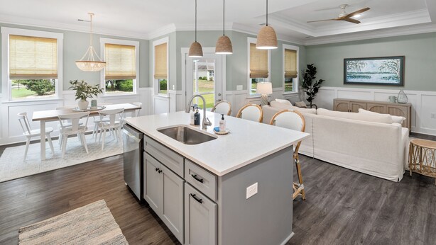 Una cocina moderna con una isla central, armarios blancos e iluminación colgante.