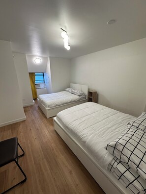 A bedroom with two beds, a window with curtains, a ceiling light, and a wooden floor. - 31 Nights or more - 3 bedroom apartment in downtown Montréal with terrace (Montréal)