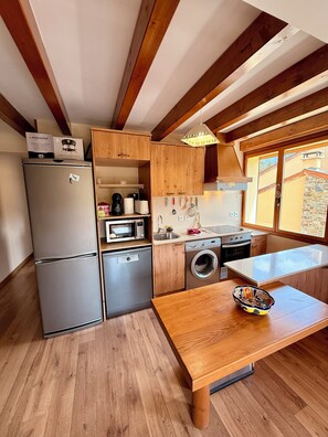 Eine kompakte Küche mit Kühlschrank, Mikrowelle, Backofen und Waschmaschine.