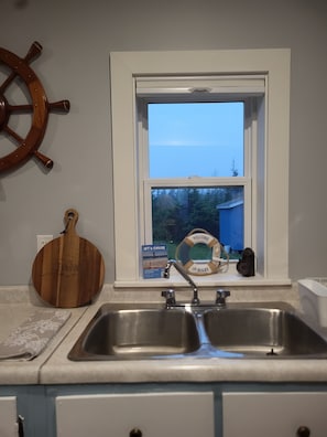 A kitchen with a double sink, a wooden cutting board, a life ring, and a 'Welcome On Board' sign.