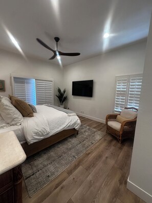 A bedroom with a bed, a chair, a ceiling fan, and a TV. - Golf course frontage with stunning mountain views in Ironwood Country club. (Palm Desert)