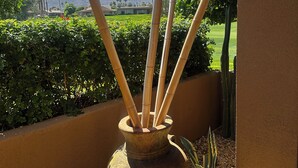 Un jarrón de cerámica grande con palitos de bambú en un balcón con vistas a un campo de golf y montañas.