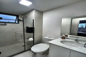 A modern bathroom with a toilet, sink, and mirror. - Modern and elegant apartment near the Olympic Park. (Rio de Janeiro)