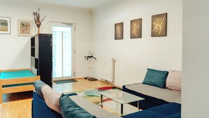 Una sala moderna con un sofá, una mesita, una cama y obras de arte en las paredes.
