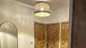 Een kamer met een houten vloer, een bankje, een spiegel en een deur.