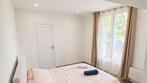 A bedroom with a bed, bedside table, and a window with curtains. - ⭐ 70m² with Terrace - Near Paris, CDG & RER B (5min) (Sevran)