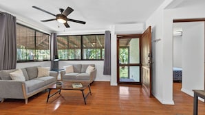 A spacious living area with a ceiling fan, two sofas, a coffee table, and large windows offering a view of greenery. - Tranquil 2-bedroom villa with AC in Playa Hermosa (Playa Hermosa)
