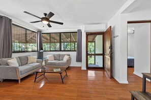 A spacious living area with a ceiling fan, two sofas, a coffee table, and large windows offering a view of greenery. - Tranquil 2-bedroom villa with AC in Playa Hermosa (Playa Hermosa)