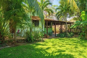 A house with a covered patio, surrounded by lush greenery and palm trees. - Tranquil 2-bedroom villa with AC in Playa Hermosa (Playa Hermosa)