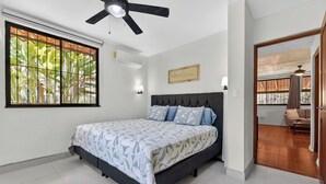 A bedroom with a bed, a ceiling fan, a window with a view, and a door leading to another room. - Tranquil 2-bedroom villa with AC in Playa Hermosa (Playa Hermosa)