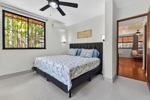 A bedroom with a bed, a ceiling fan, a window with a view, and a door leading to another room. - Tranquil 2-bedroom villa with AC in Playa Hermosa (Playa Hermosa)