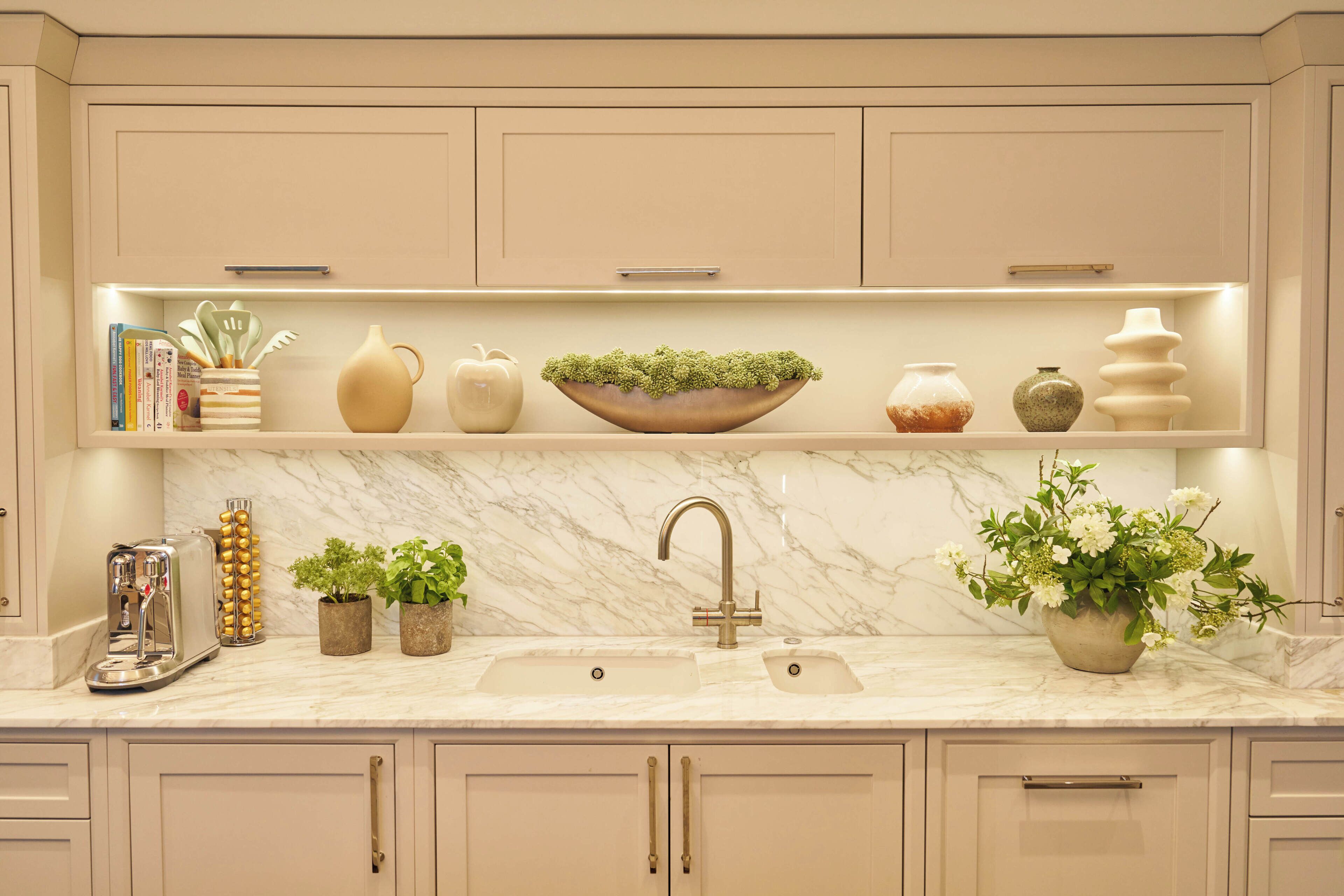 A kitchen with a marble countertop, a double sink, and various kitchen items.