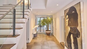 Un intérieur moderne agrémenté d’un escalier, d’une grande plante en pot et d’une œuvre d’art remarquable au mur.