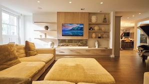 Un salon moderne avec un canapé, un téléviseur et des étagères décoratives.