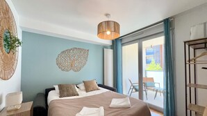 A bedroom with a bed, a wall decoration, a hanging light fixture, a balcony with a chair, and a wooden shelf. - T4 5 personnes à 300m du Lac (Aix-les-Bains)