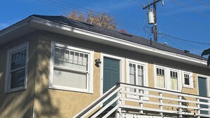A two-story building with a balcony, a staircase, and a power line overhead.