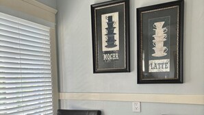 Two black leather chairs, a small wooden table, and two framed pictures on the wall.