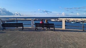 Een steiger met bankjes met uitzicht op een jachthaven met boten.