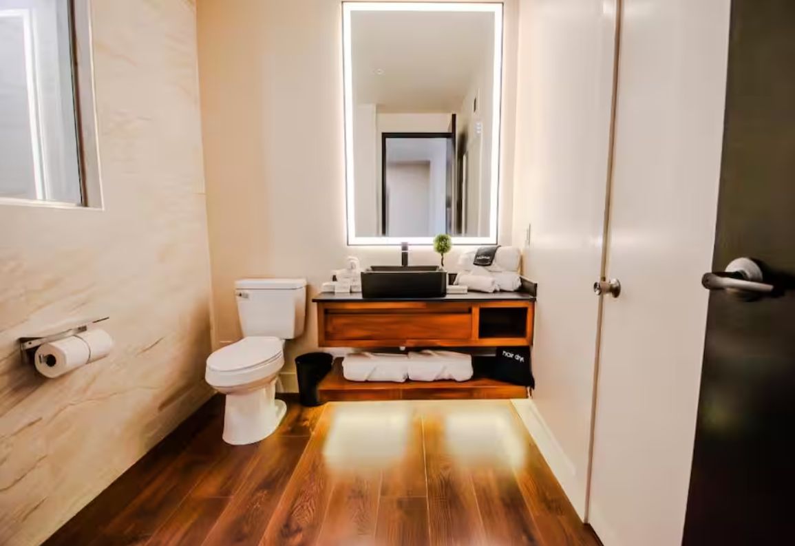 A bathroom with a toilet, a sink, a mirror, and a wooden vanity.