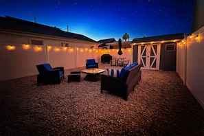 Un patio al aire libre con asientos, luces colgantes y una fuente de agua.