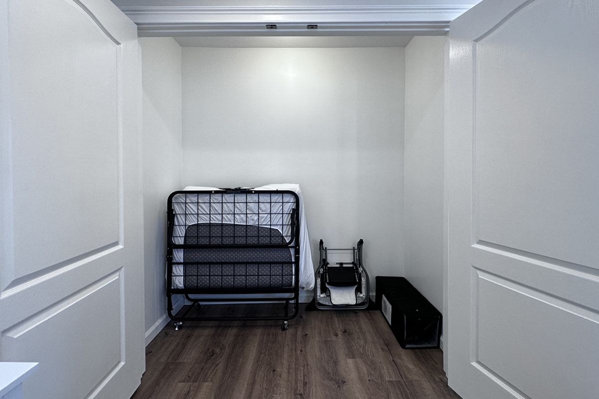 A narrow room with a bunk bed, a wheelchair, and a small black suitcase.