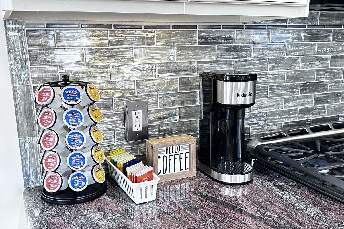 Una cocina con cafetera, portacápsulas de café y un letrero que dice 'Hello Coffee'.