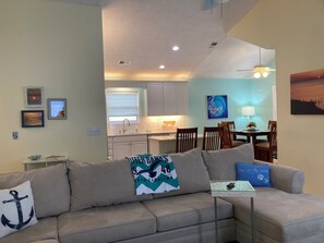 A living room with a sofa, a glass coffee table, and a dining area with a table and chairs.