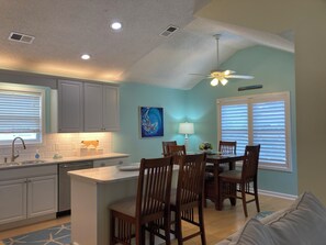 A kitchen with a dining area, a ceiling fan, and a window with blinds.
