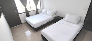 A hotel room with two beds, a nightstand, and a window with curtains.