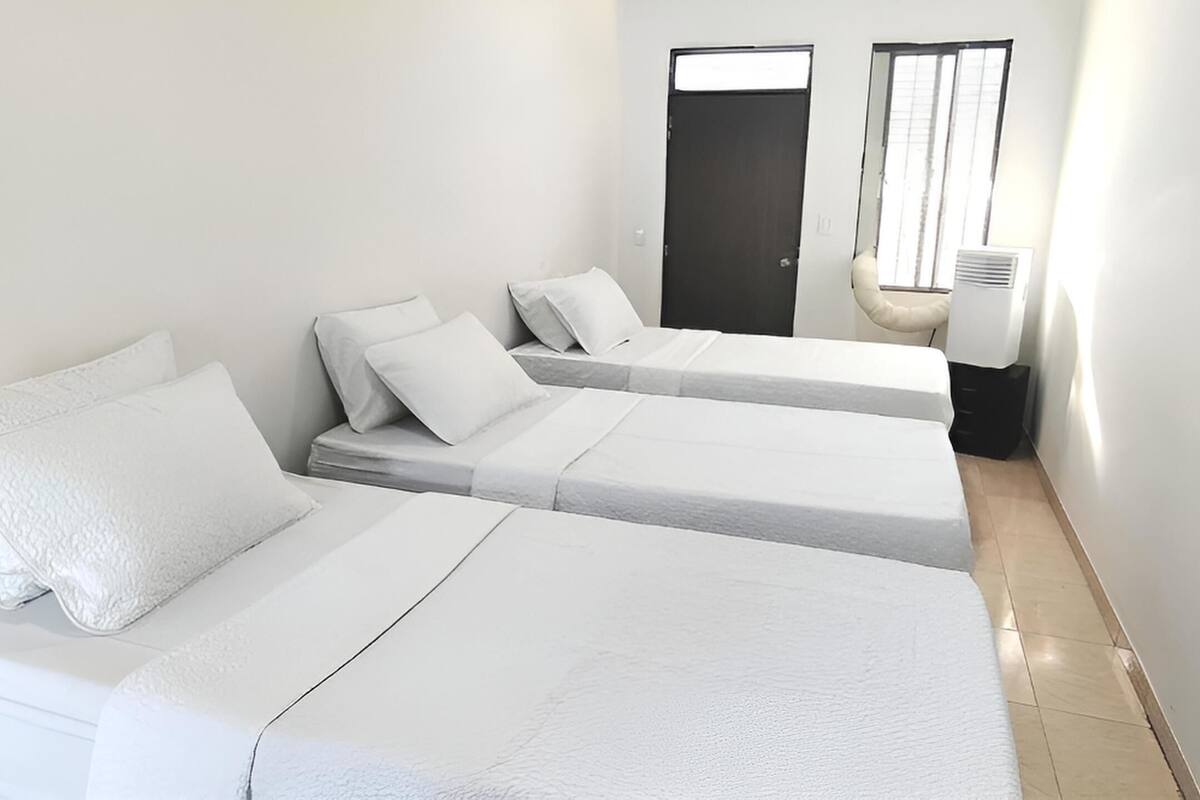 A hotel room with two beds, a mirror, a door, and a window.