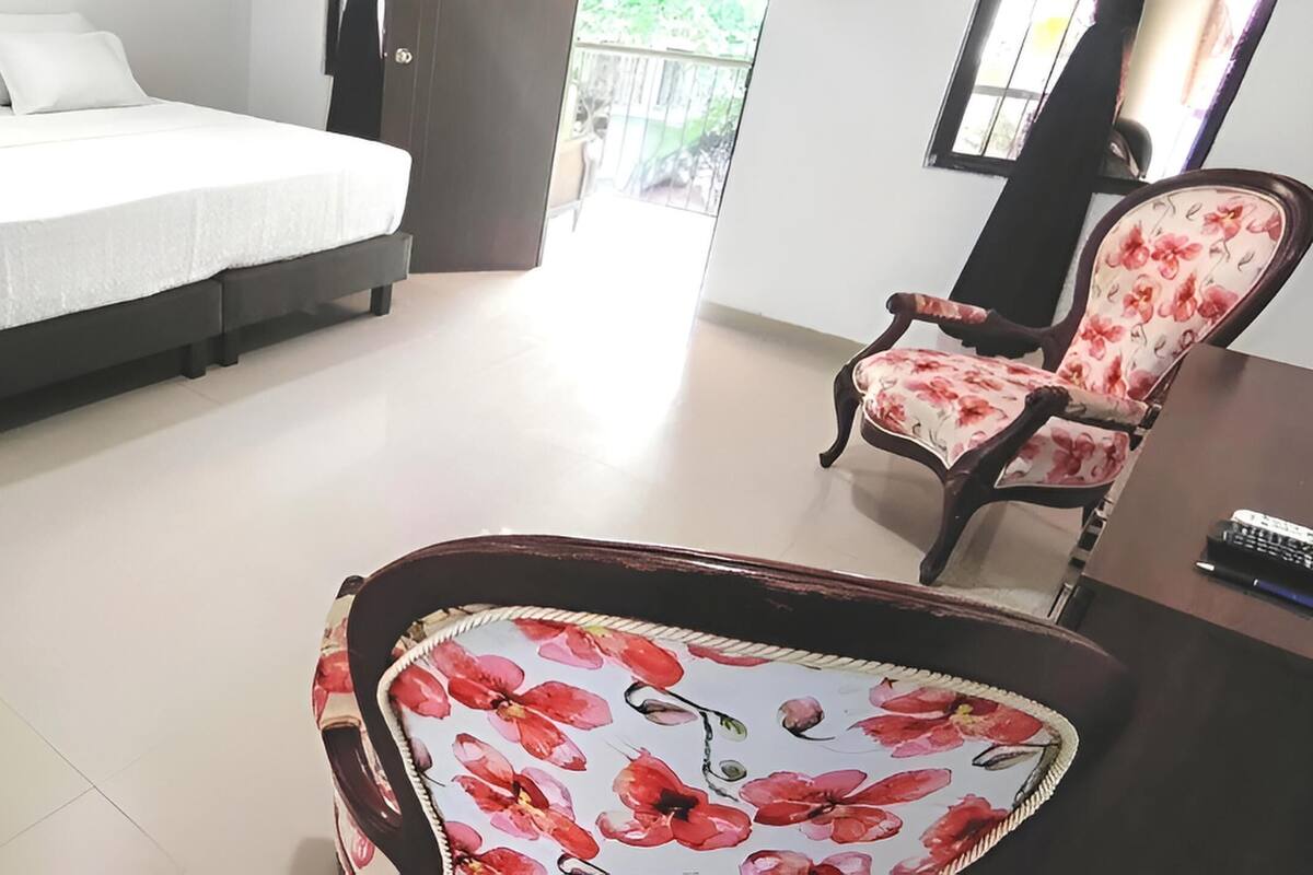 A bedroom with a bed, a chair, a desk, and a nightstand.