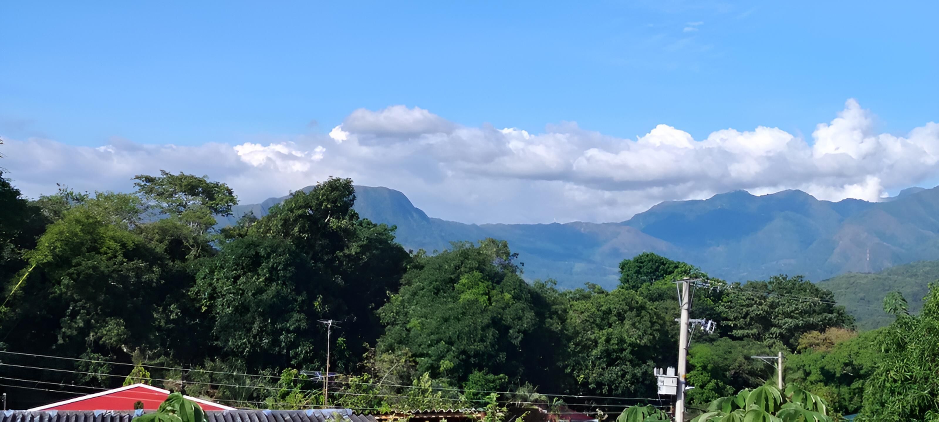 A mountainous landscape with dense greenery and a clear sky.
