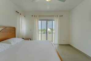 A bedroom with a bed, curtains, a ceiling fan, and a view through a glass door. - Prime Apartment With Fast Internet & Washer in SOV (Sosúa)
