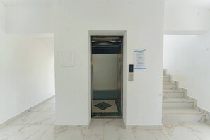 An elevator in a hallway with a marble floor, a staircase to the right, and a wall-mounted sign. - Prime Apartment With Fast Internet & Washer in SOV (Sosúa)
