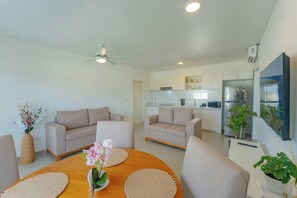 A modern living room with a round wooden table, beige sofas, and a ceiling fan. - Prime Apartment With Fast Internet & Washer in SOV (Sosúa)
