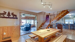 Un intérieur en bois comprenant une table à manger, des bancs, un canapé, un escalier et un coin cuisine.
