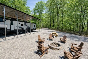 A covered RV parking area with a fire pit and Adirondack chairs. - Knotty Acres RV Retreat @ Lake Cumberland (Albany)