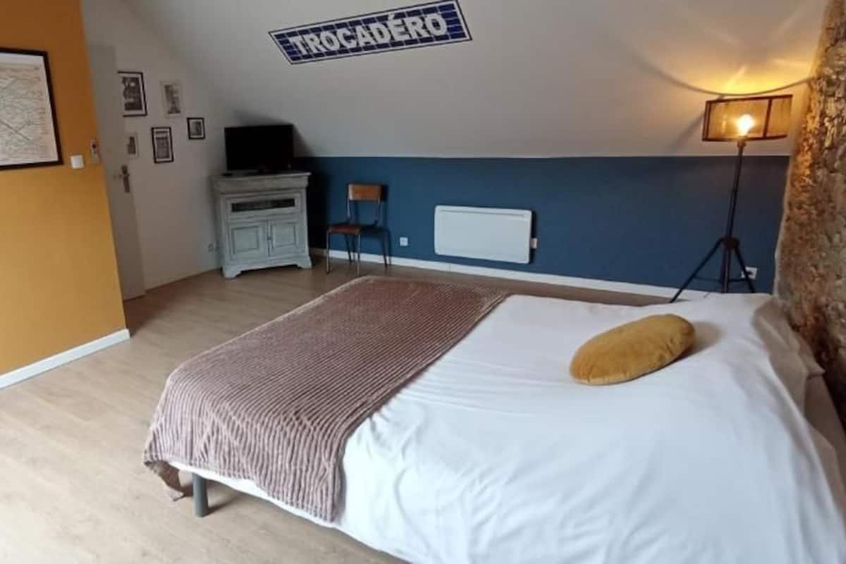 Une chambre à coucher avec un lit, une carte accrochée au mur, une commode, une chaise et une lampe.