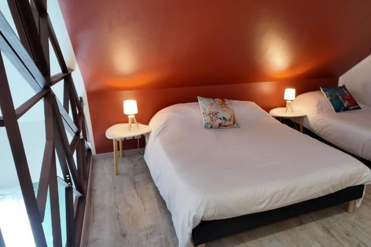 Une chambre avec deux lits, chacun étant équipé d’une lampe de chevet et d’un oreiller.
