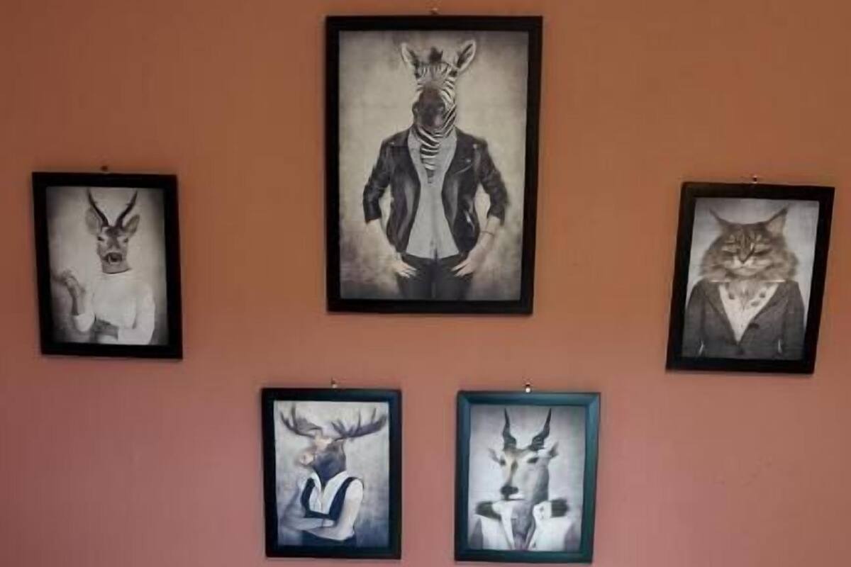 Une chambre à coucher avec un lit, des oreillers et quatre œuvres d’art encadrées accrochées au mur.
