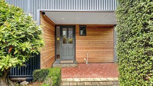 A modern building with a grey door, wooden paneling, and a small window above the door.