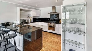 A modern kitchen with a central island, built-in oven, and a wine rack.